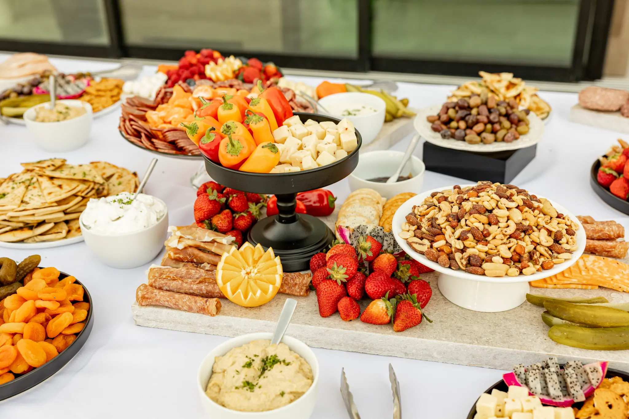 Colorful charcuterie spread with fruits, meats, cheeses, and crackers on white linen