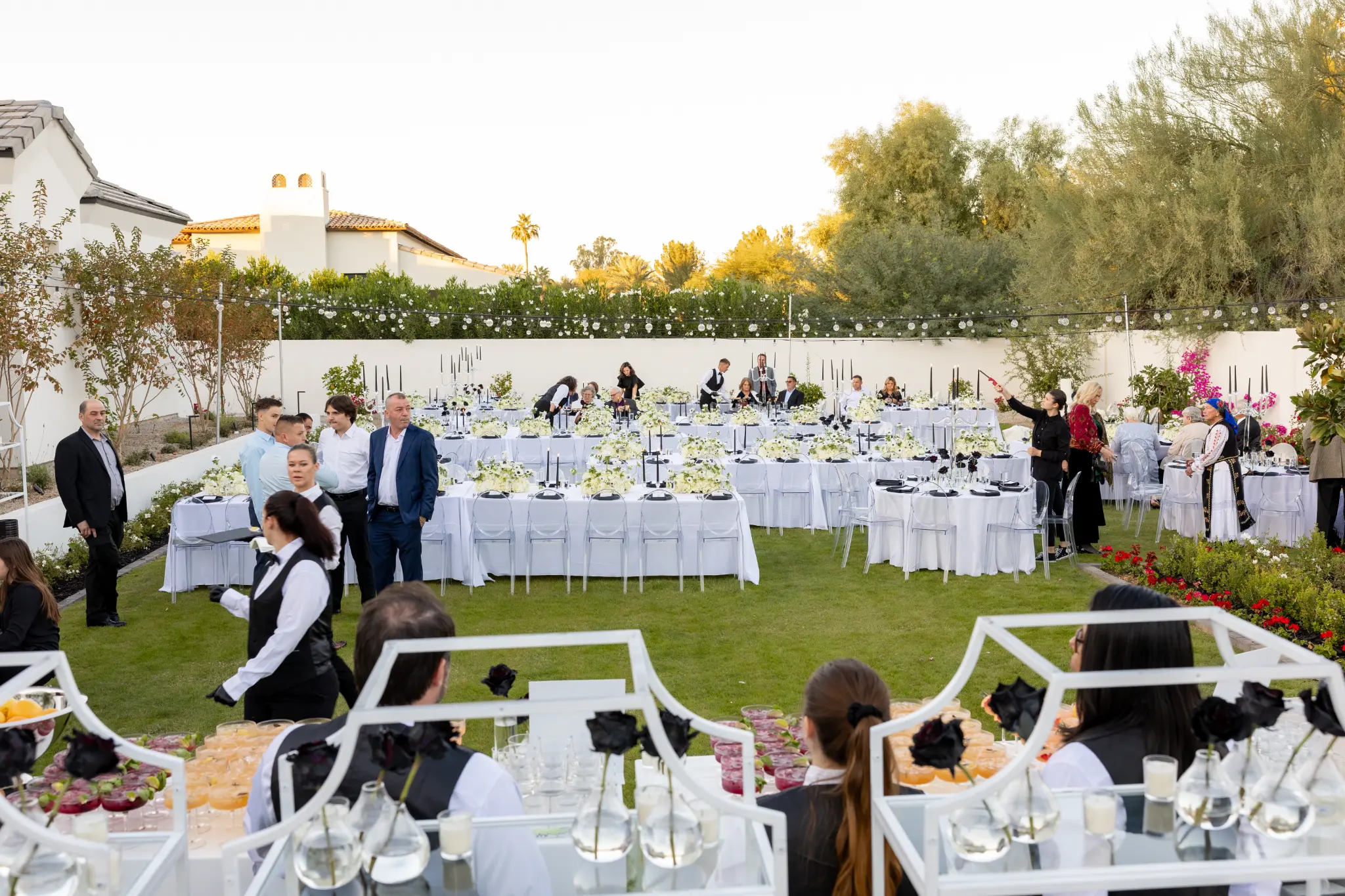 Elegant outdoor wedding reception with long tables, white florals, and string lights