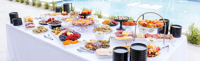 Abundant poolside grazing table with charcuterie, fruits, and pastries