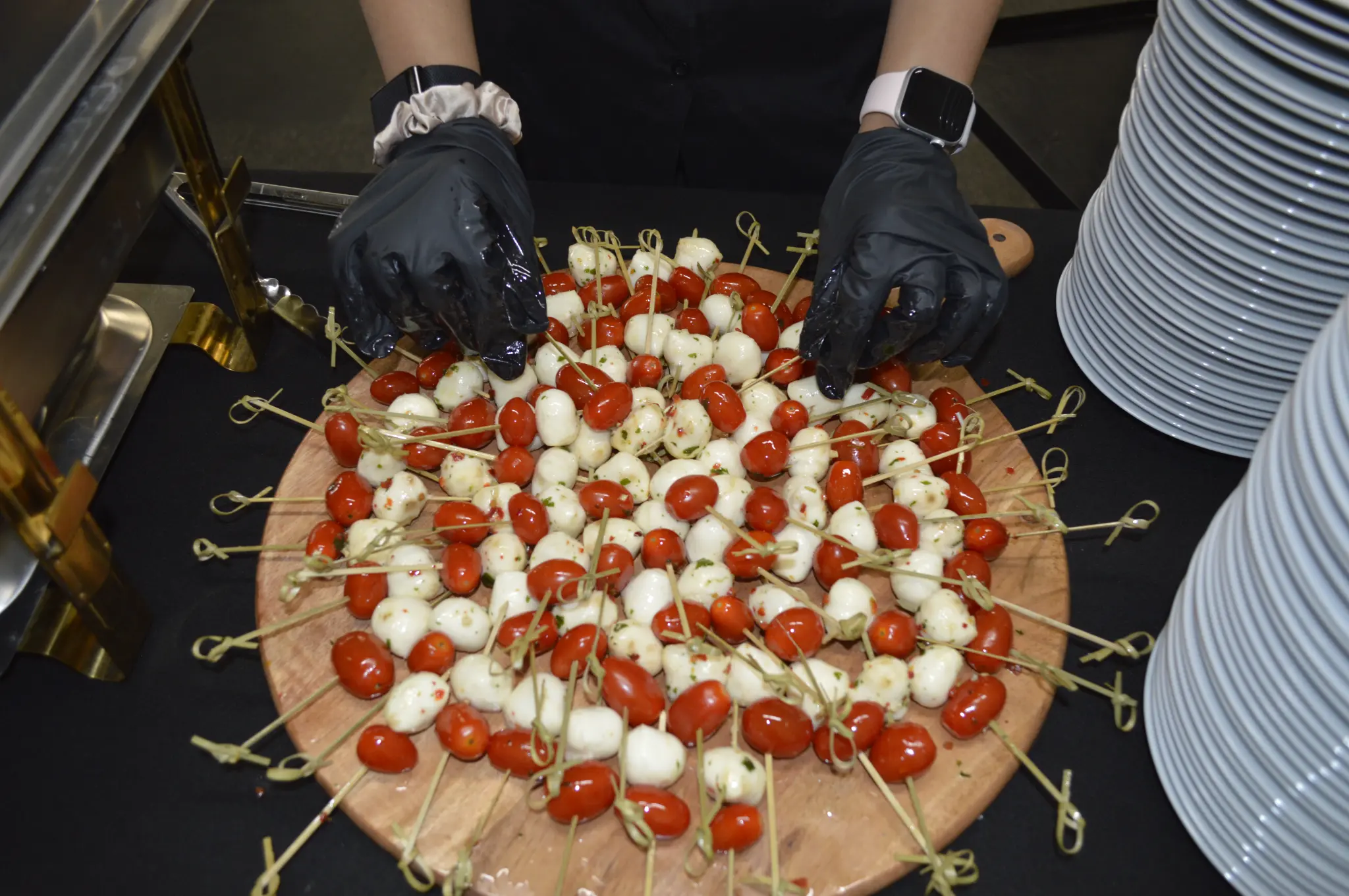 Chef arranging caprese skewers with cherry tomatoes and fresh mozzarella